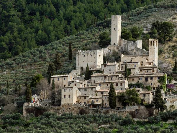  Castle of Pissignano Alto, with medieval towers and stone houses nestled among olive groves and wooded hills 